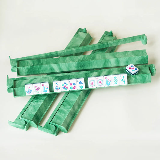 A complete set of four jade green swirl patterned mahjong racks stacked together with colorful American mahjong tiles displayed on one rack.