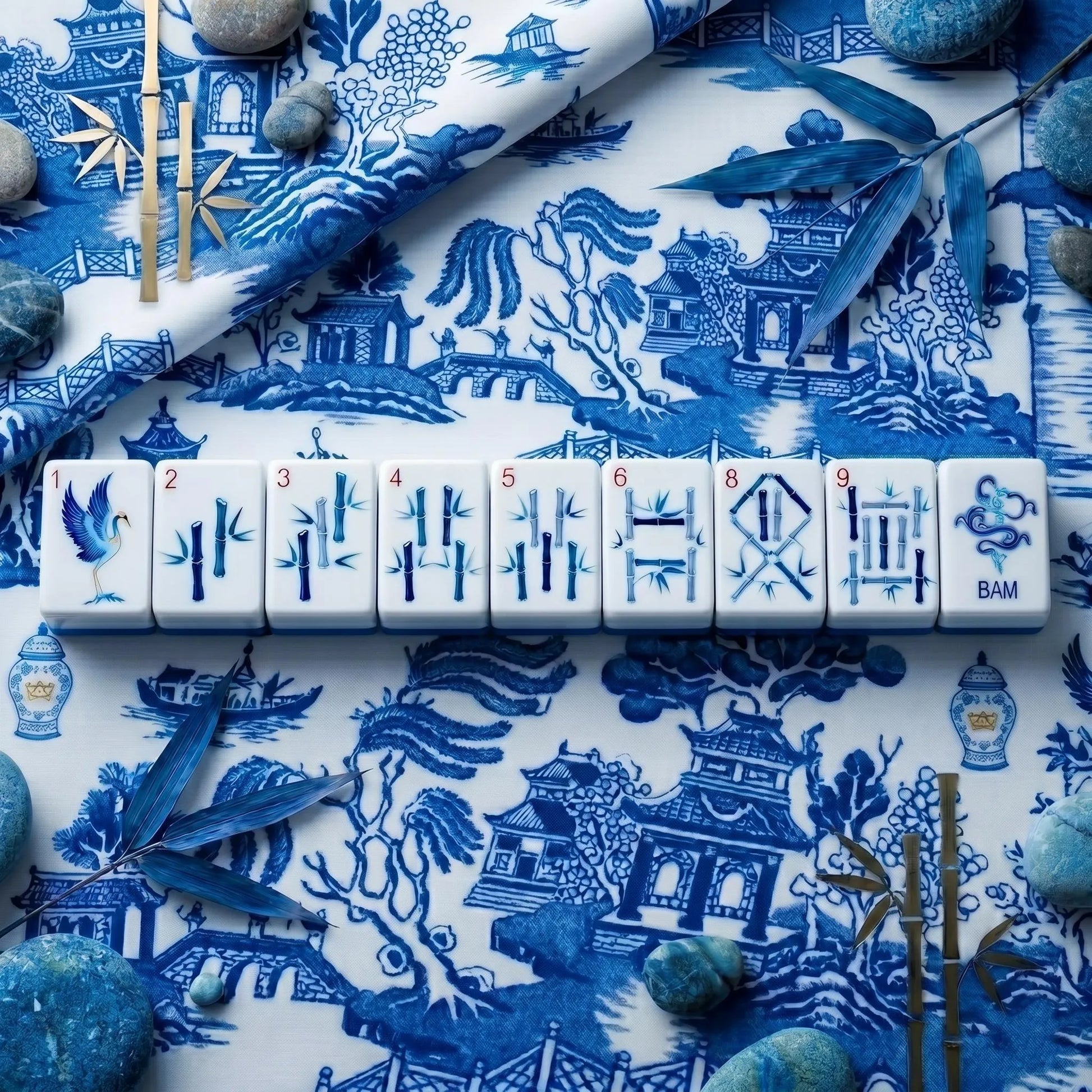 A lineup of indigo bamboo tiles and crane 1-bam displayed flat against a classic blue and white toile fabric background.