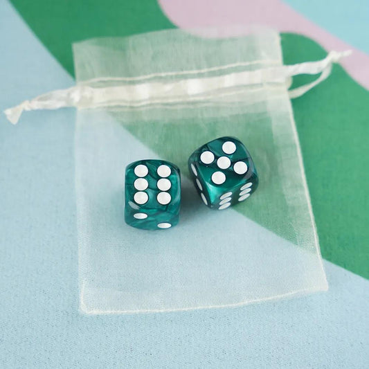 A pair of deep emerald teal marbled acrylic mahjong dice with crisp white pips in a sheer organza pouch.