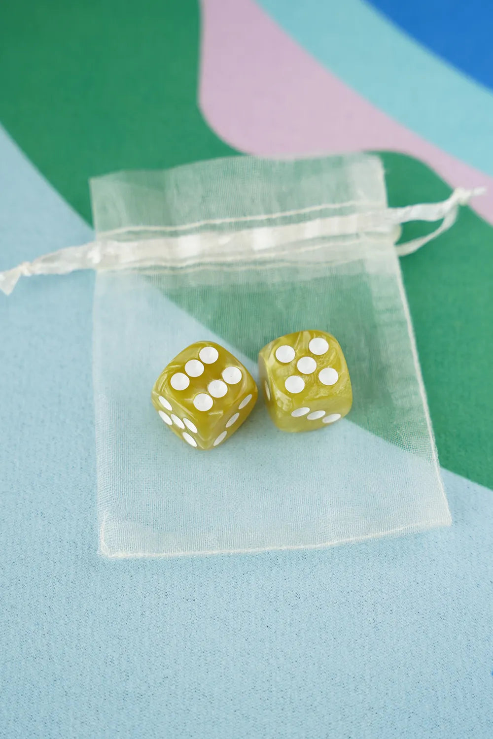 A pair of olive green 5/8 inch marbled acrylic mahjong dice with white pips in a sheer organza pouch.
